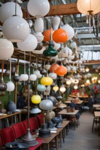 Pendant lights and table lamps are displayed on the wall of a flea market storefront.