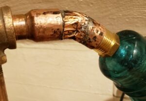 Copper pipe with worn joint and blue fitting.