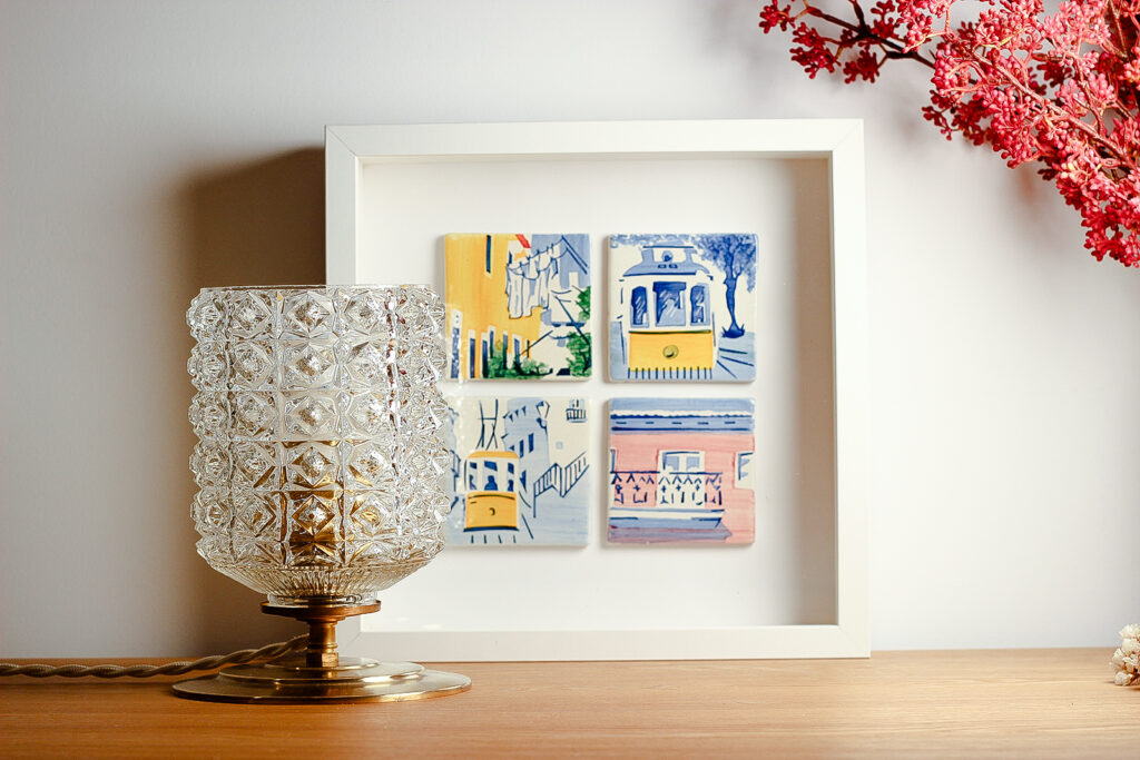 Lampe à poser vintage et cadre avec illustrations sur commode.