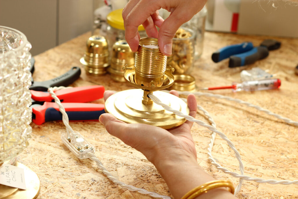 Assemblage artisanal d’un luminaire en laiton avec câble textile torsadé dans l’atelier Alfama Chic