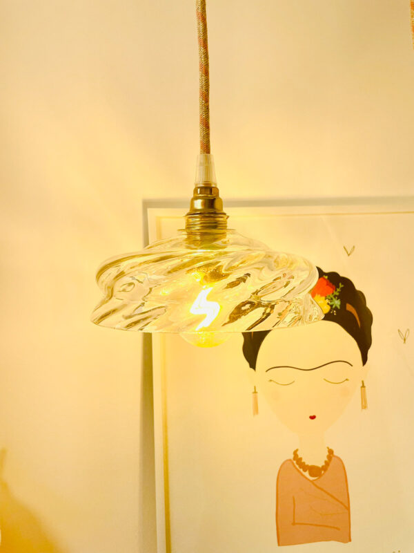 Hanging light above illustrated wall art. Artistic hanging lamp with a glass globe mounted on a brass socket above a wall drawing.