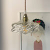 Hanging light above illustrated wall art. Artistic hanging lamp with a glass globe mounted on a brass socket above a wall drawing.