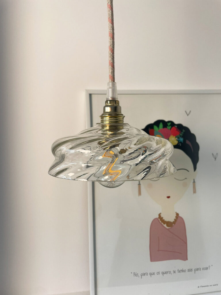 Lampe suspendue artistique avec un globe en verre monté sur une douille en laiton au-dessus d'un dessin mural.