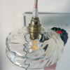 Hanging light above illustrated wall art. Artistic hanging lamp with a glass globe mounted on a brass socket above a wall drawing.