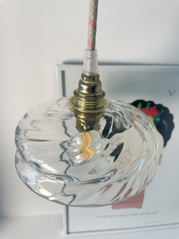 Hanging light above illustrated wall art. Artistic hanging lamp with a glass globe mounted on a brass socket above a wall drawing.