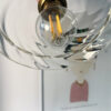 LED light bulb in decorative glass fixture. Hanging light above illustrated wall art. Artistic hanging lamp with a glass globe mounted on a brass socket above a wall drawing.