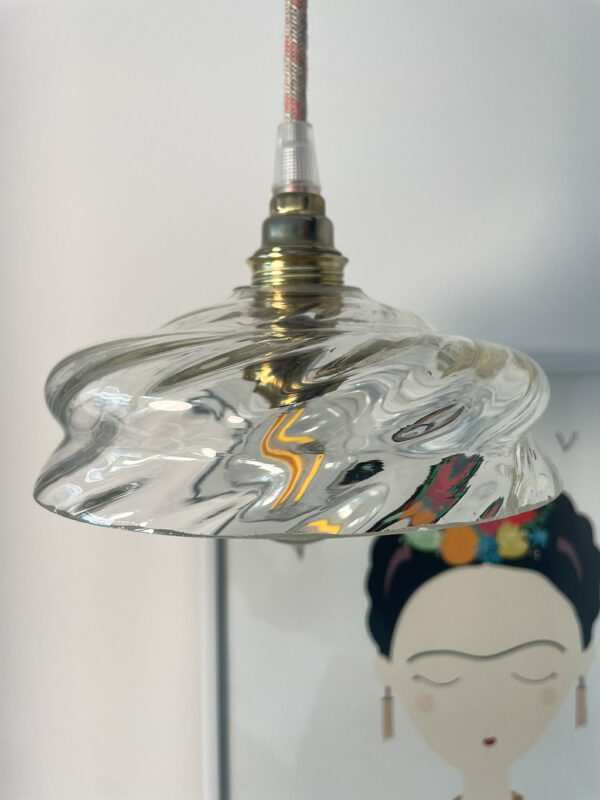 Hanging light above illustrated wall art. Artistic hanging lamp with a glass globe mounted on a brass socket above a wall drawing.