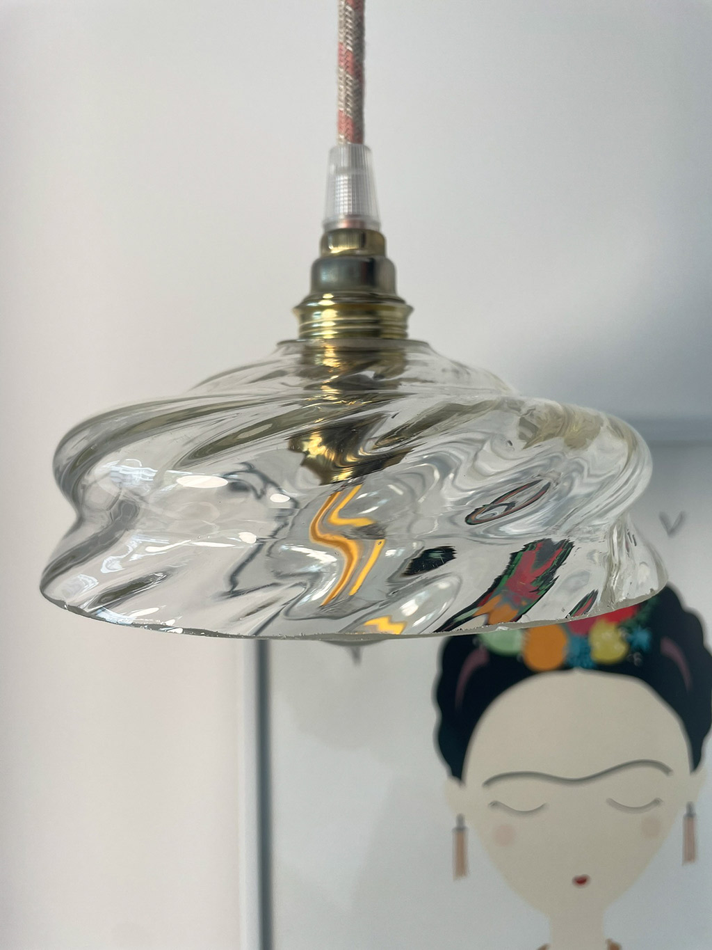 Hanging light above illustrated wall art. Artistic hanging lamp with a glass globe mounted on a brass socket above a wall drawing.