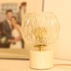 Lampe à poser Vintage composée d'un globe en verre ciselé et d'une base en marbre blanc et veines beiges.