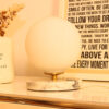 Lampe à poser en opaline, sphérique, lumineuse sur socle en marbre blanc et veines grises.