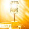 Vintage table lamp composed of a chiseled glass globe and a white marble base with beige veins. The lamp is illuminated.
