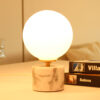 Lampe à poser en opaline, sphérique, lumineuse sur socle en marbre blanc et veines grises.