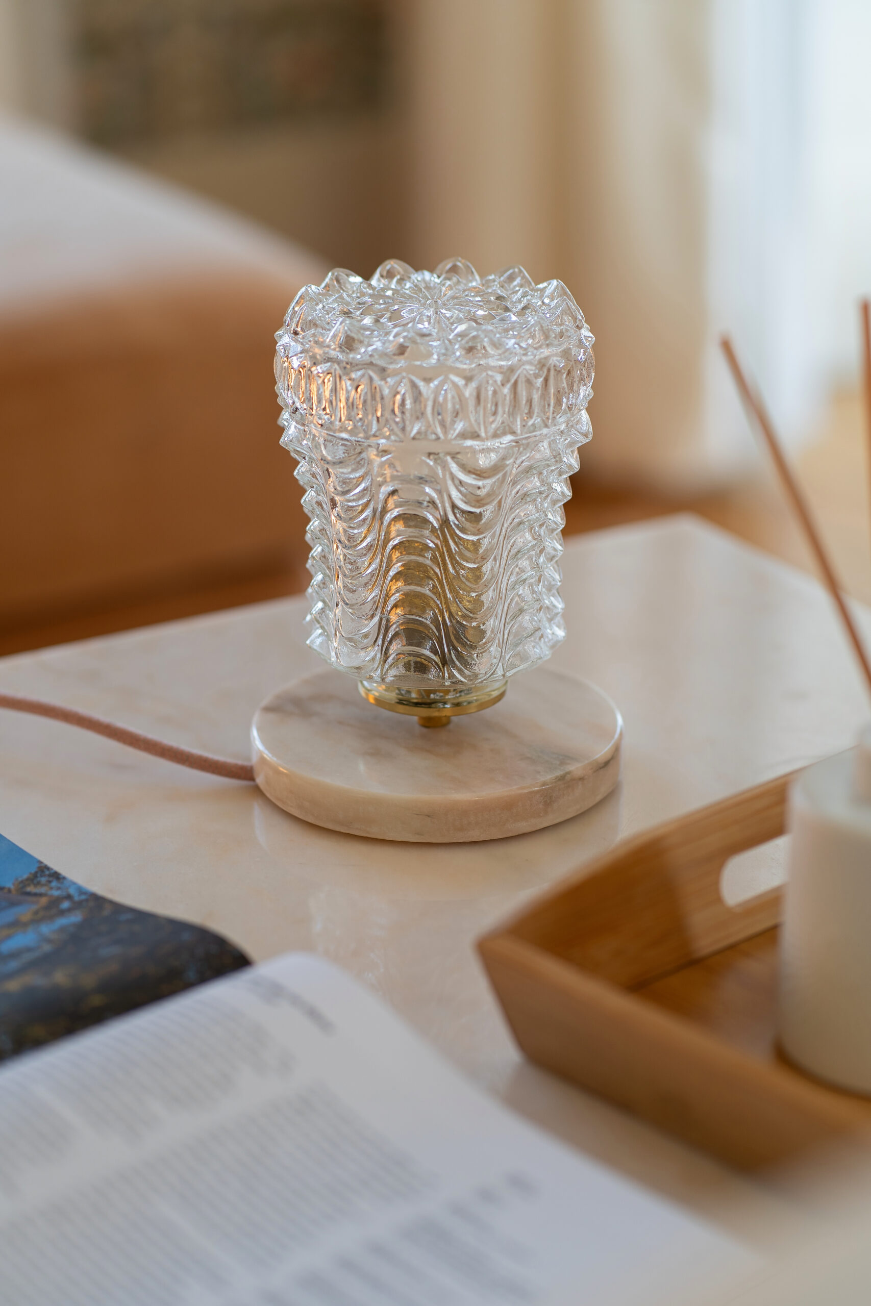 Candeeiro em vidro texturizado com base em mármore a difundir uma luz suave num interior elegante.