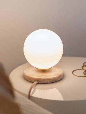 Candeeiro de mesa esférico Isabelle em vidro branco que difunde uma luz suave sobre a mesa de cabeceira