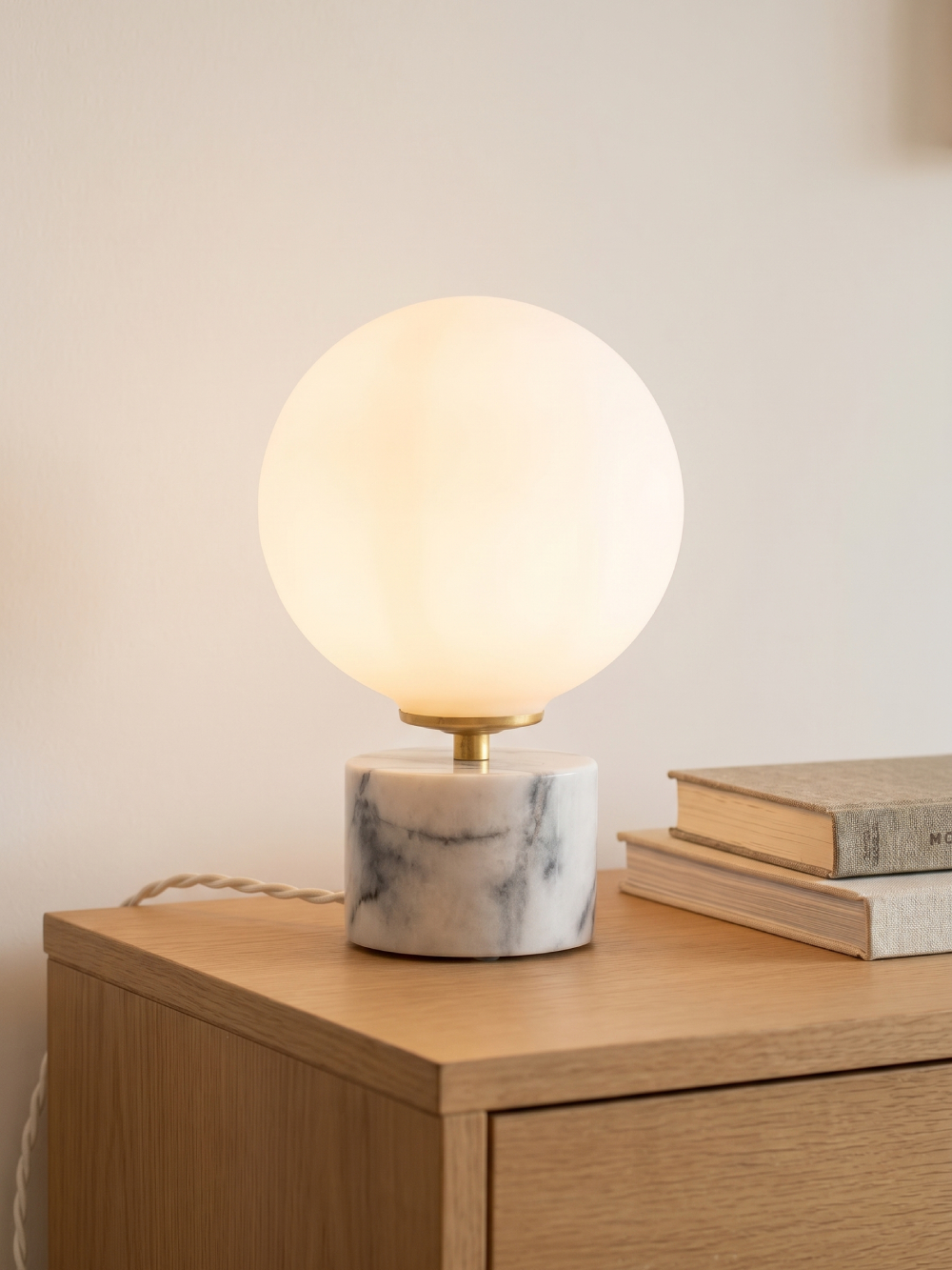 Laura ball lamp lit on oak sideboard — opaline globe casting a warm glow and grey-veined Estremoz marble base — Alfama Chic