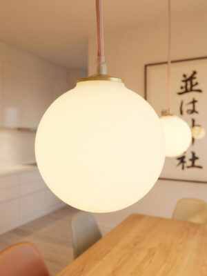 Grande plano da suspensão vintage Louna da Alfama Chic, detalhe do globo em vidro opalino luminoso e do casquilho em latão com cabo de algodão rosa, segunda suspensão Louna e caligrafia japonesa desfocadas em segundo plano, sala de jantar Japandi slow déco