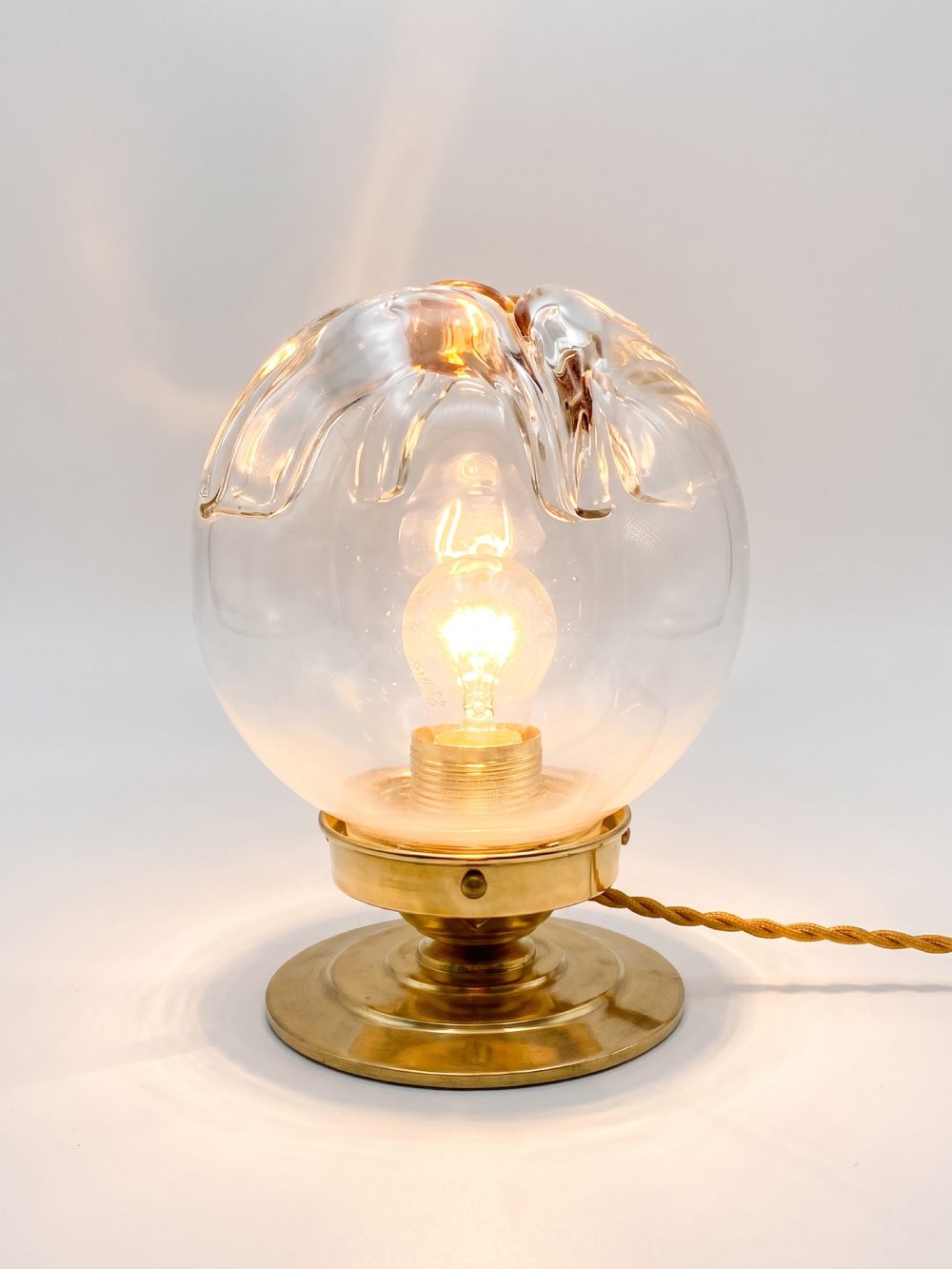 Vue de face lampe vintage globe verre style Murano soufflé sur socle laiton massif, câble torsadé doré, fond neutre